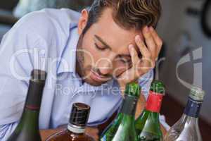 Drunk businessman looking at many spirit bottles