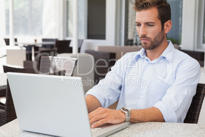 Happy businessman working on laptop at table