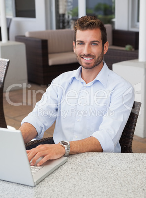 Smiling businessman working on laptop at table