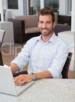 Smiling businessman working on laptop at table