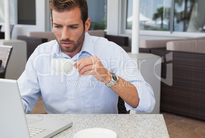 Concentrating businessman working with laptop drinking coffee