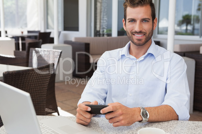 Happy businessman sending a text at table