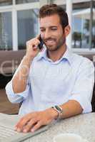 Happy businessman talking on phone using his laptop