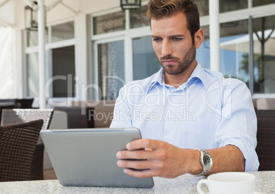 Serious young businessman working on tablet pc