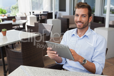 Happy young businessman working on tablet