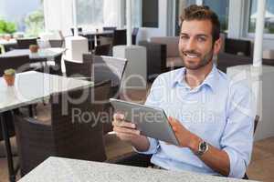 Happy young businessman working on tablet