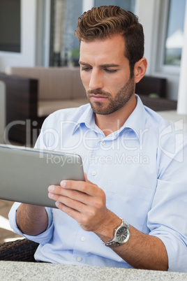 Serious young businessman working on tablet