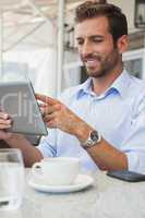 Cheerful young businessman working on tablet