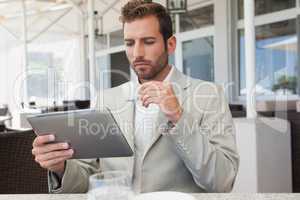 Handsome young businessman working on tablet drinking espresso
