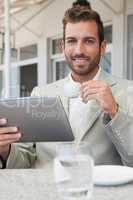 Happy young businessman working on tablet drinking espresso