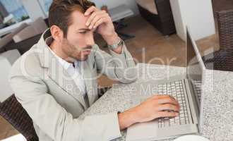 Stressed businessman working with his laptop at table