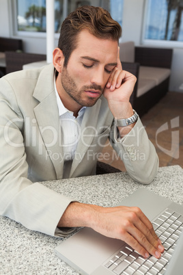 Exhausted businessman working with his laptop at table