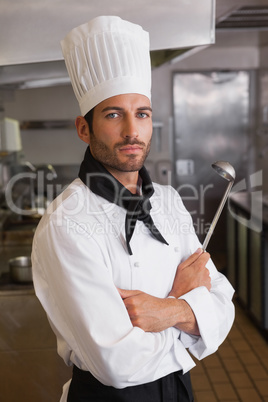 Serious chef looking at camera with arms crossed holding ladle