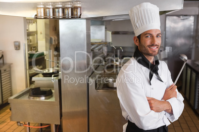Happy chef looking at camera with arms crossed holding ladle