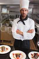 Focused chef looking at camera behind counter of desserts