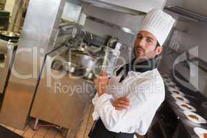Focused chef looking at camera with arms crossed holding ladle