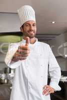 Happy young chef looking at camera showing thumb up