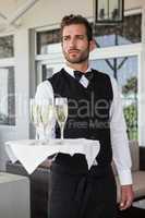Handsome waiter holding tray of champagne