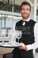 Handsome waiter holding tray of wineglasses