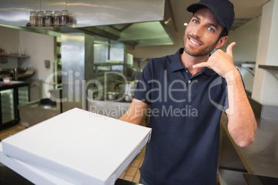 Pizza delivery man holding pizza boxes making a phone gesture