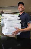 Cheerful pizza delivery man holding many pizza boxes