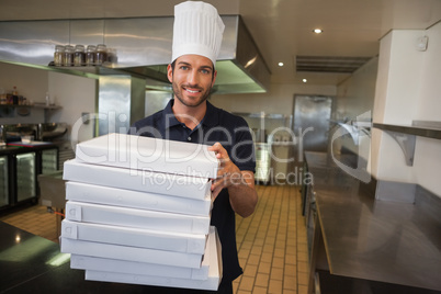 Smiling pizza chef holding stack of pizza boxes