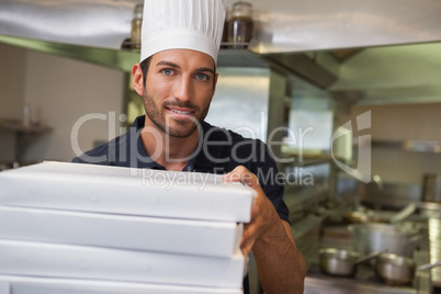 Happy pizza chef holding stack of pizza boxes