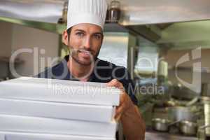 Happy pizza chef holding stack of pizza boxes