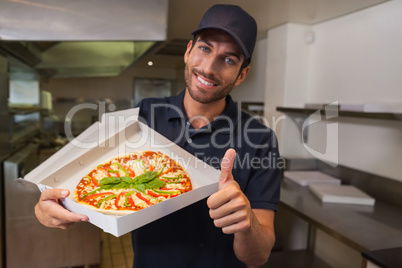 Happy pizza delivery man showing fresh pizza and thumbs up