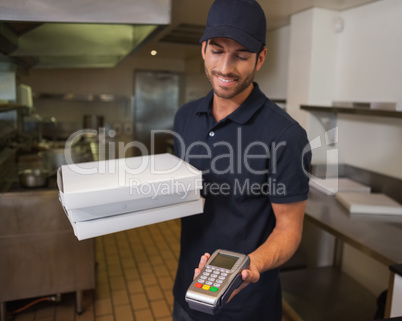 Happy pizza delivery man holding credit card machine