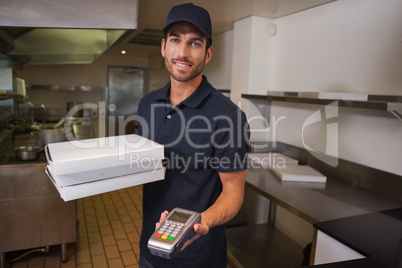 Smiling pizza delivery man holding credit card machine