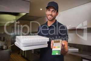 Cheerful pizza delivery man holding credit card machine
