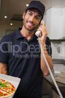 Happy pizza delivery man taking an order over the phone