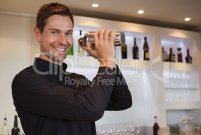 Smiling bartender shaking cocktail