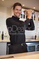 Happy bartender shaking cocktail