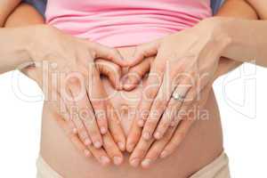 Expectant parents making a heart shape on mothers baby bump