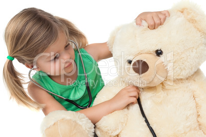 Cute little girl playing doctor with her teddy bear