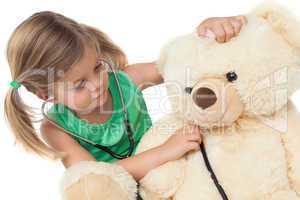 Cute little girl playing doctor with her teddy bear