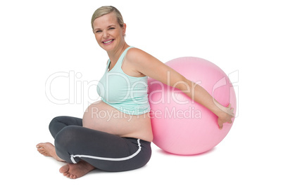 Pregnant woman leaning against pink exercise ball