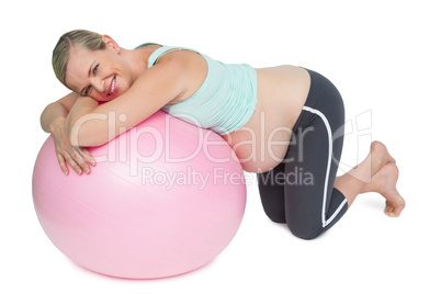 Cheerful pregnant woman kneeling against pink exercise ball