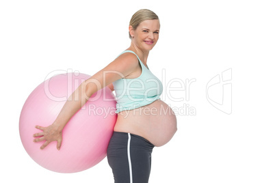 Pregnant woman holding pink exercise ball behind her back Pregnant woman holding pink exercise ball behind her back