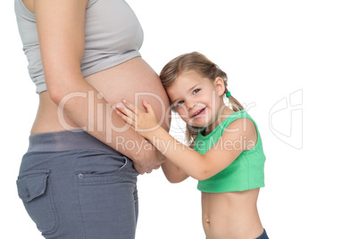 Little girl listening to her mothers baby bump