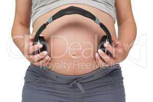 Pregnant woman holding headphones over bump