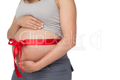 Pregnant woman with a red bow around her bump