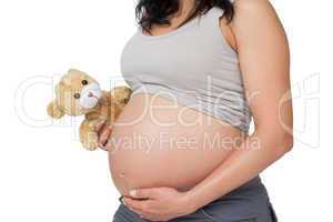 Pregnant woman touching her bump holding a teddy
