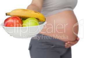 Pregnant woman showing fruit bowl to camera