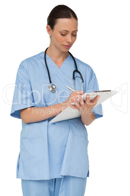 Concentrating nurse writing on clipboard