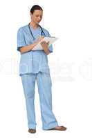 Smiling pretty nurse in scrubs writing on clipboard