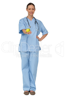 Smiling nurse in scrubs holding green apple