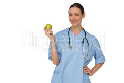 Happy nurse in scrubs holding green apple